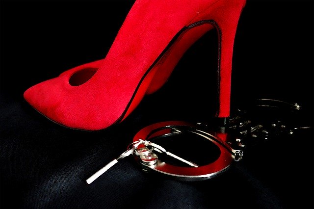 a red high-heel stepping on cuffings